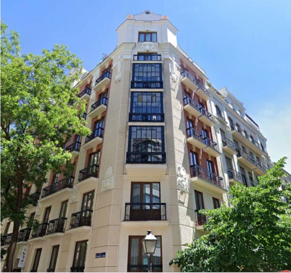 Fachada clásica con balcones señoriales y arboleda en edificio prime del barrio de Salamanca, Madrid — propiedad seleccionada por Coco House