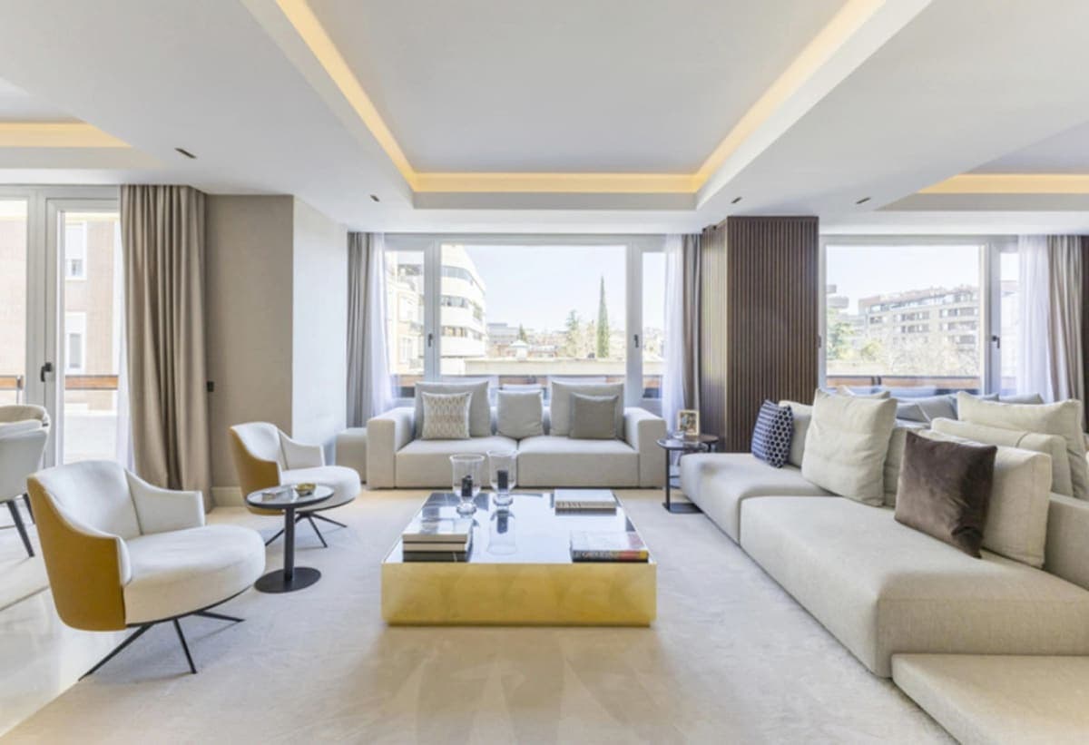 Salón con doble zona de estar y mesa baja dorada — propiedad de lujo en Paseo de la Castellana, Madrid (Coco House)