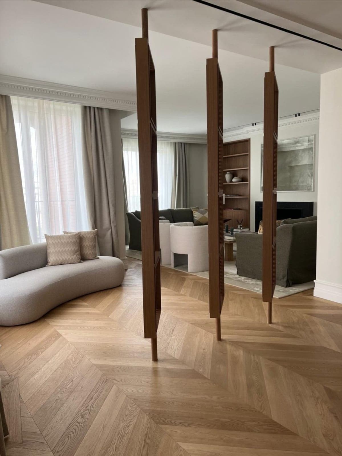 Sofá curvo de boucle, parquet en espiga y biombo de madera en piso señorial del barrio de Salamanca, Madrid — Coco House