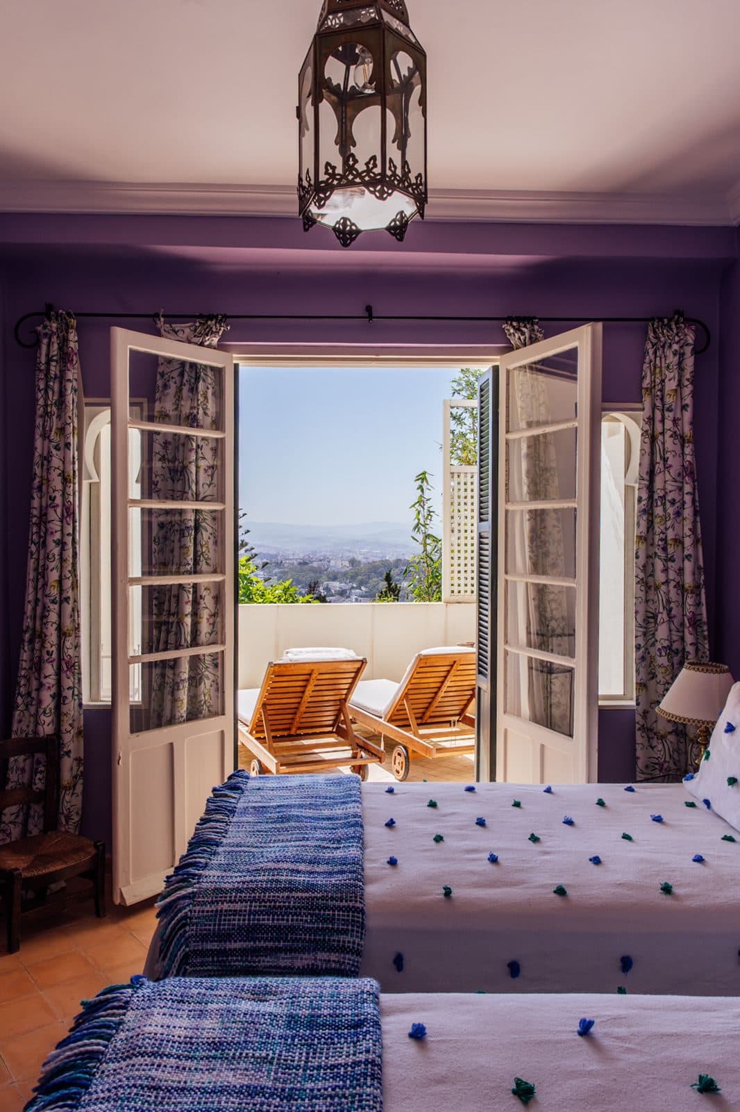 Dar Chal — Tánger, Marruecos Suite principal en lila con puertas abiertas a una terraza privada con vistas sobre Tánger — Dar Chal (Coco House)