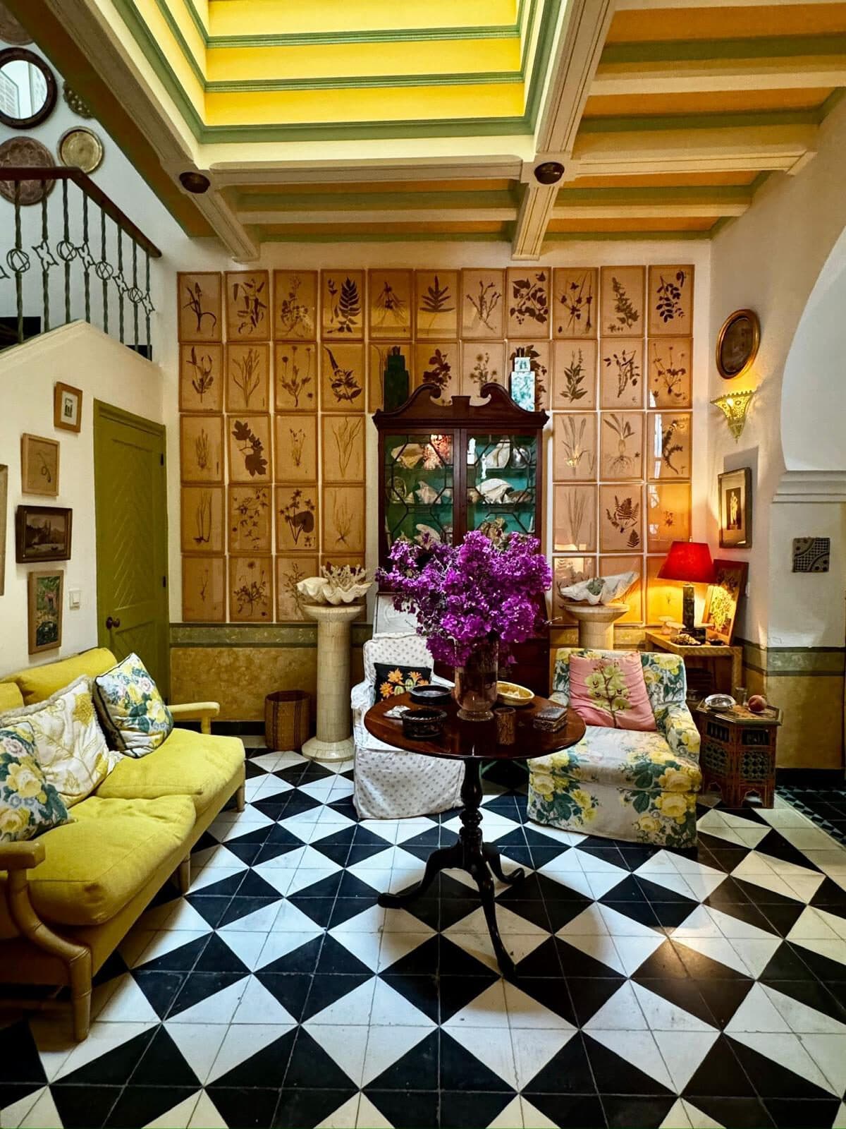 Riad en la Kasbah — Kasbah, Tánger Salón con pared de botánica prensada, suelo de damero blanco y negro y sofá amarillo — riad en la Kasbah, Tánger (Coco House)